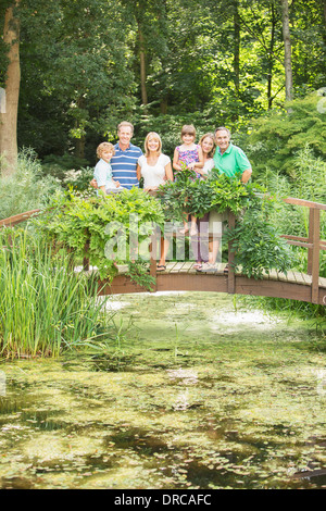 Multi-generation family standing on wooden footbridge sur l'étang Banque D'Images
