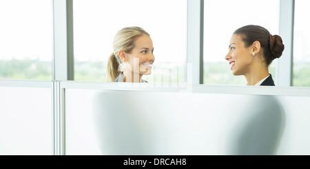 Businesswomen talking derrière la moitié wall in office Banque D'Images