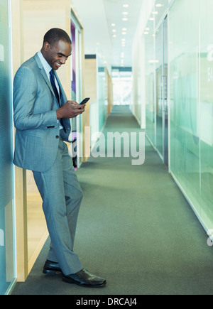 Businessman using cell phone in office corridor Banque D'Images