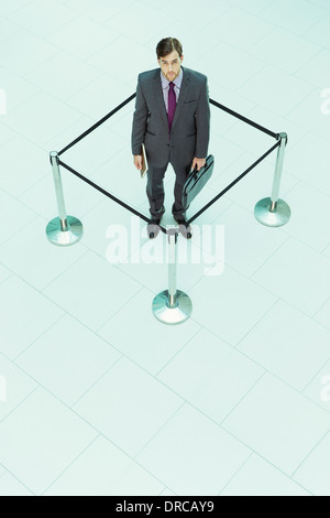 Businessman standing in roped-off square Banque D'Images