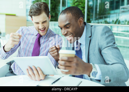 Hommes d'cheering at digital tablet Banque D'Images