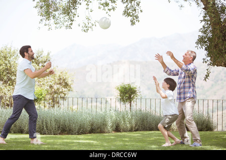 Multi-generation family playing volleyball in backyard Banque D'Images