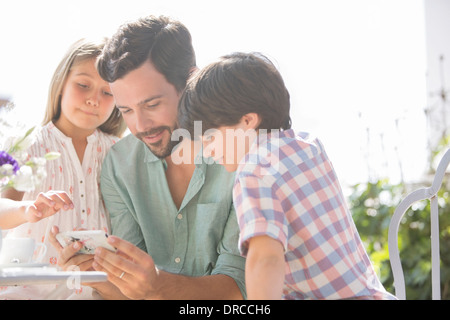 Le père et les enfants à l'aide de cell phone outdoors Banque D'Images