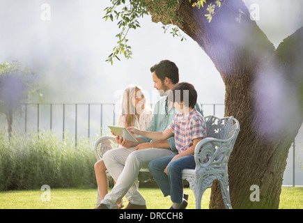 Le père et les enfants sitting on bench in park Banque D'Images