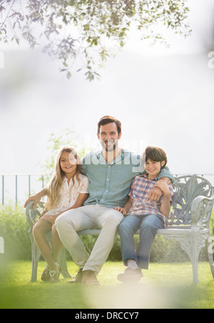 Le père et les enfants se détendre sur banc de parc Banque D'Images