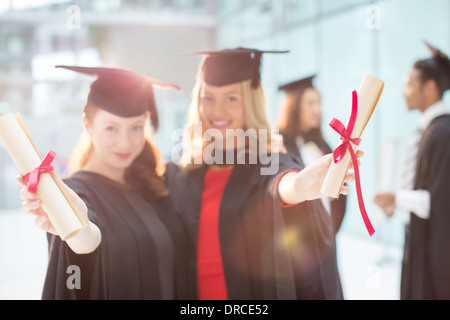 Les diplômés Smiling holding diplomas Banque D'Images