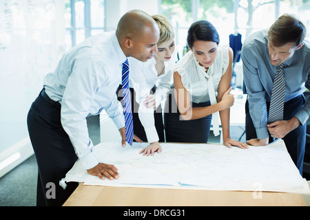 Les gens d'affaires examining blueprints in office Banque D'Images