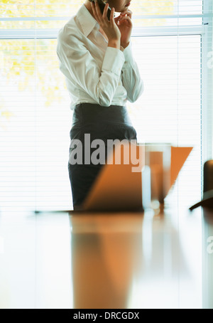 Businesswoman talking on cell phone in office Banque D'Images