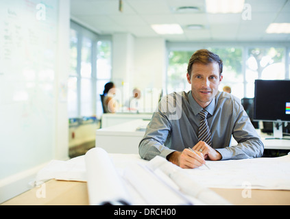 Businessman reading blueprints in office Banque D'Images