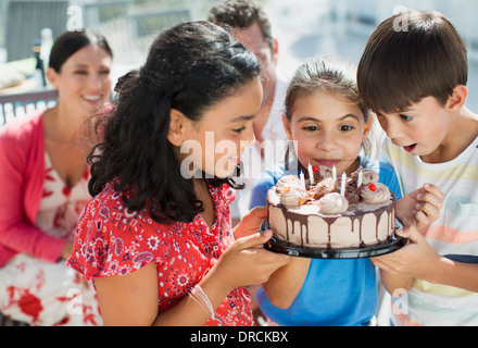 Enfants holding birthday cake outdoors Banque D'Images