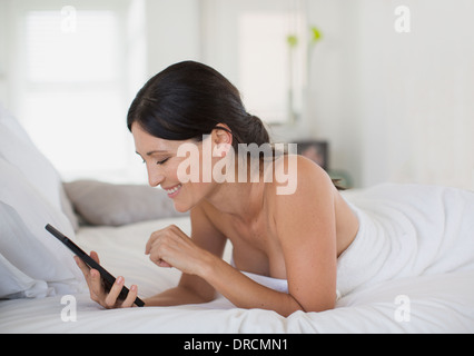 Woman using digital tablet on bed Banque D'Images
