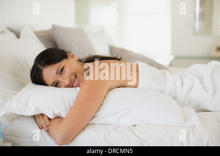 Woman hugging pillow on bed Banque D'Images