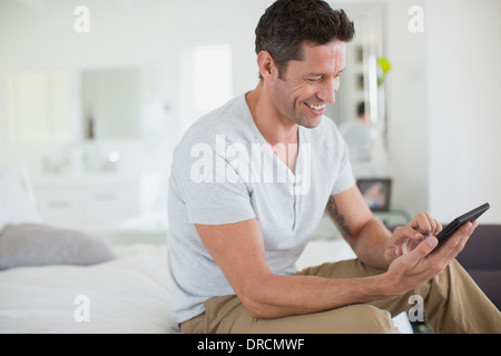 Man using digital tablet on bed Banque D'Images