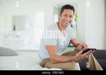 Man using digital tablet on bed Banque D'Images