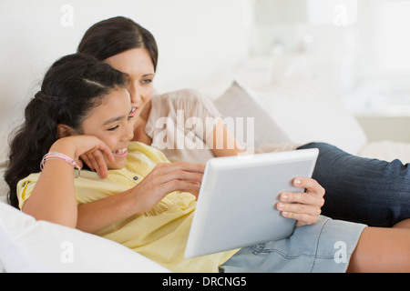 Mère et fille using digital tablet on bed Banque D'Images