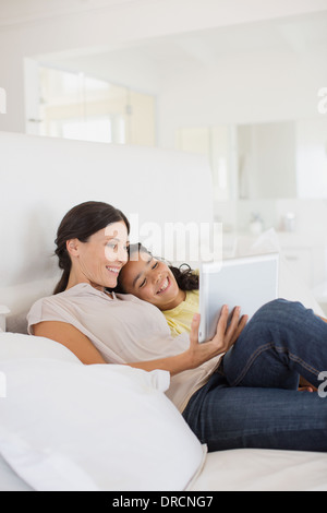 Mère et fille using digital tablet on bed Banque D'Images