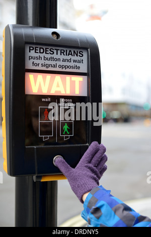 Appuyer sur le bouton d'un jeune enfant à un franchissement routier au courant de l'accent sur la sécurité routière sign Banque D'Images