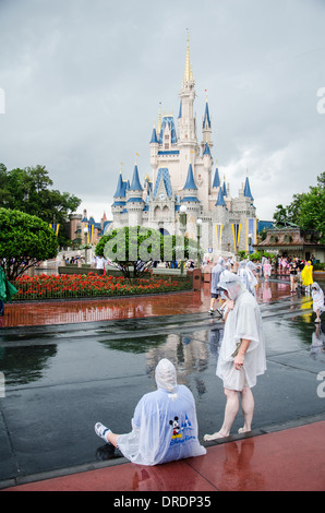 Les familles dans la pluie Ponchos à Walt Disney World, Orlando, Floride, avec le Magic Kingdom Château en arrière-plan. Banque D'Images