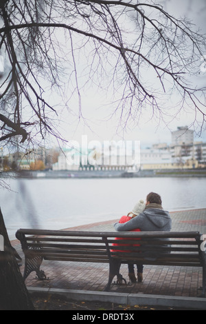 Image de l'affectueux jeune couple assis sur le banc dans le parc Banque D'Images