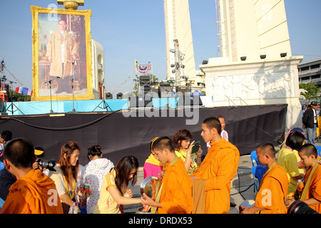 Des manifestants anti-gouvernement qui mérite à des moines bouddhistes de payer pour le Roi Bhumibol Adulyadej de Thaïlande sur son 86e naissance Banque D'Images