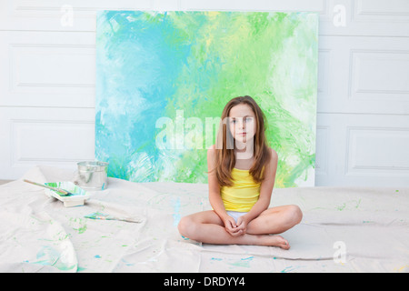 Jeune fille assise en face de la peinture de couleur bleu et vert Banque D'Images