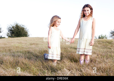 Soeurs en robes standing in field Banque D'Images