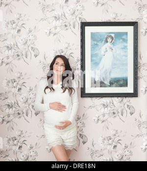 Femme enceinte en face de mur floral Banque D'Images