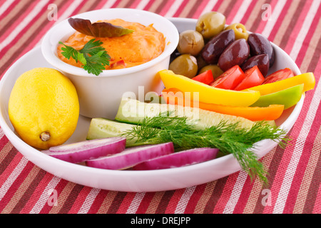 Des légumes frais, des olives, du citron et de la sauce au fromage sur la plaque. Banque D'Images