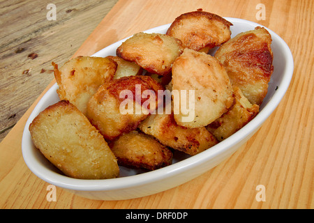 Croustillant de pommes de terre dans un plat de service contre une table de cuisine rustique traditionnel Banque D'Images