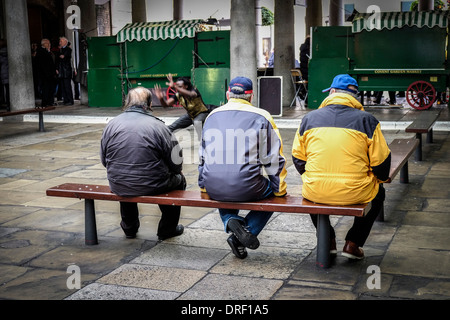 Trois hommes de regarder un spectacle de rue dans le Hall Nord à Covent Garden. Banque D'Images