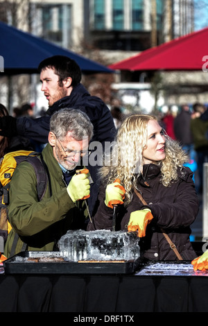 Les membres du public d'essayer la sculpture sur glace dans le cadre du London Festival des sculptures en glace. Banque D'Images