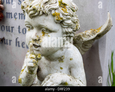 Un marbre chérubin soulève notre silence à côté d'une pierre tombale dans un cimetière anglais. Banque D'Images