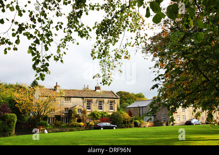 Un village avec des maisons vertes sous une voûte de branches avec des couleurs d'automne. Banque D'Images