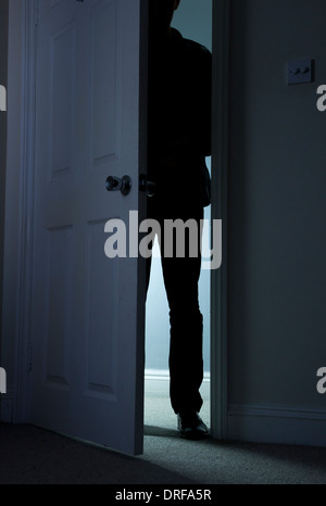 Silhouette d'un homme debout dans le noir, dans une porte ouverte. Banque D'Images