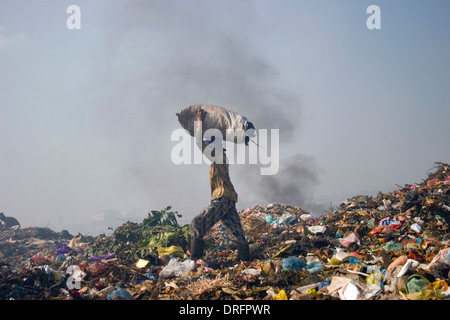 Un homme qui est une chasse travailleur est porteur d'une large sac à la décharge de Stung Meanchey toxiques à Phnom Penh, Cambodge. Banque D'Images