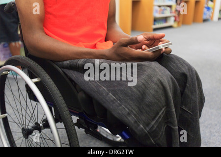 L'homme avec la méningite dans un fauteuil roulant à l'aide de téléphone cellulaire Banque D'Images