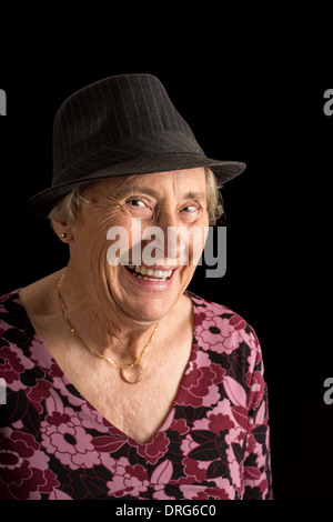 Senior lady portant un fedora rire isolated on black Banque D'Images