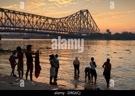 L'Inde, le Bengale occidental, Kolkata (Calcutta) hommes lave près de Howrah Bridge au coucher du soleil Banque D'Images