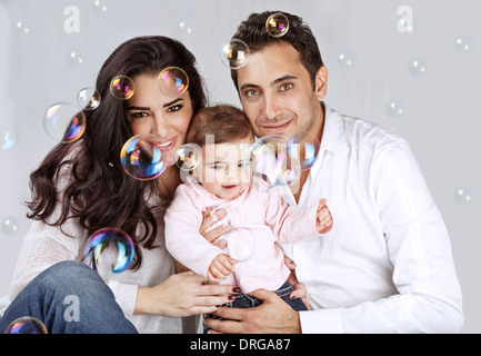 Portrait of cute baby girl arabe avec Mère et père jouant avec des bulles de savon, profitant de la famille, l'amour et de bonheur concept Banque D'Images