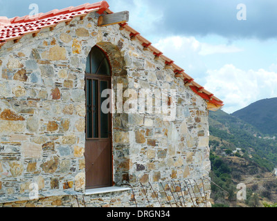 Maison ancienne en pierre en Grèce avec porte en bois et toit en terre cuite rouge Banque D'Images