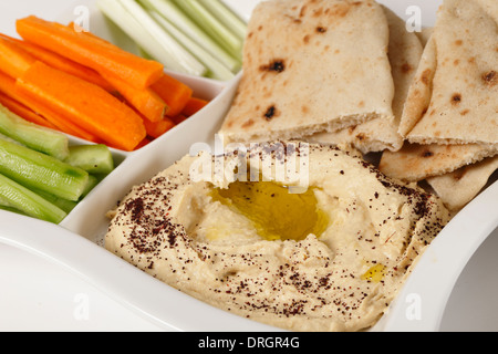 Un bac d'hummus dip, pain, bâtonnets de carotte, céleri et concombre. Banque D'Images