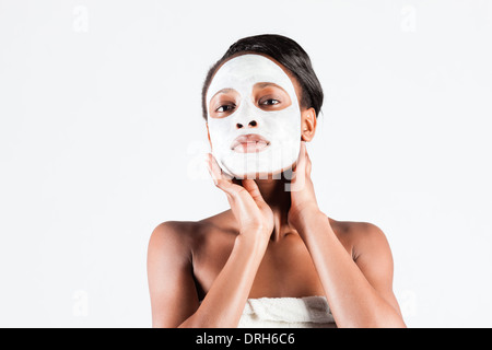 Jeune femme africaine en Studio faisant corps avec le masque facial rafraîchissant pour les jeunes et une belle peau et de détente Banque D'Images