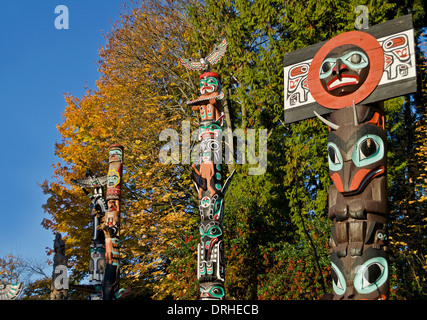 Les Premières Nations totems au parc Stanley à Vancouver (Canada). Les totems sculptés par des artistes autochtones. Couleur d'automne dans les arbres. Banque D'Images