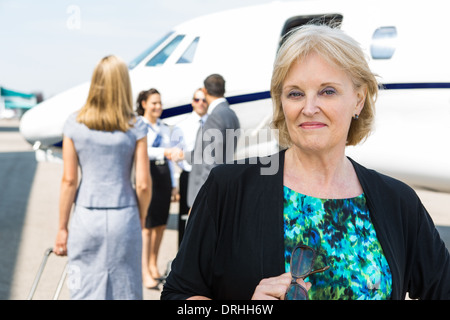 Portrait of smiling Businesswoman contre Private Jet Banque D'Images