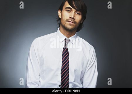 Portrait de beau jeune homme d'affaires regardant caméra contre un arrière-plan gris. Les jeunes asiatiques. Banque D'Images