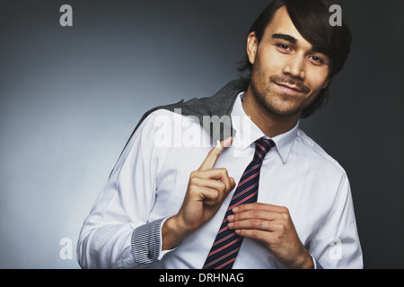 Portrait de beau mâle entrepreneur tenant son manteau sur l'épaule à la caméra en souriant. Asian businessman smiling. Banque D'Images