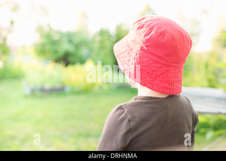 Scène d'été tranquille. Jeune fille assise dans le jardin, regarder les plantes et fleurs. Banque D'Images