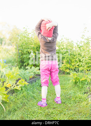 Scène d'été tranquille. Young Girl standing in garden, regarder les plantes et fleurs. Banque D'Images