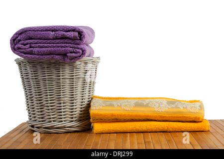 Panier en osier plein de serviettes de couleur propre sur une table en bois, sur fond blanc Banque D'Images