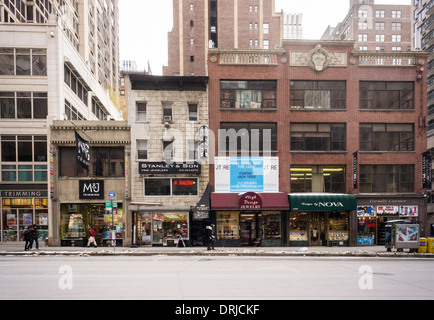 Comme les magasins immobilier non aménagés le long du côté est de la Sixième Avenue, dans le centre de l'habillement à New York Banque D'Images